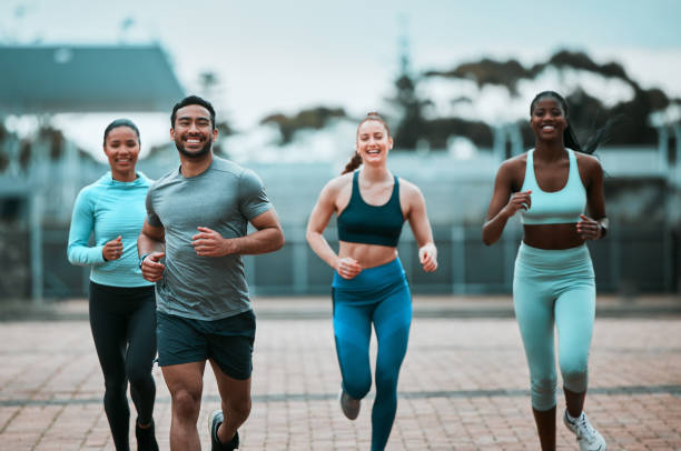 Diverse group of runners smiling together on a paved community path